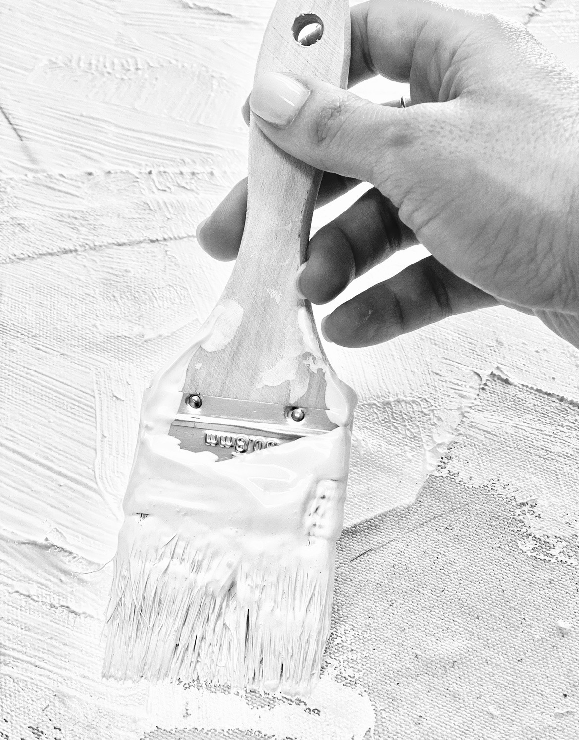 Julie applying white paint to a textured canvas